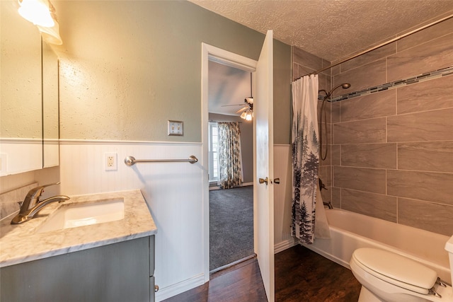 bathroom featuring wainscoting, toilet, a textured ceiling, a ceiling fan, and wood finished floors
