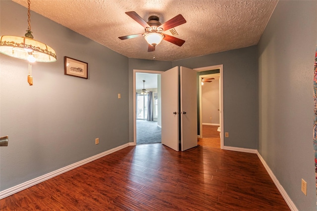 unfurnished room with baseboards, a ceiling fan, a textured ceiling, and wood finished floors