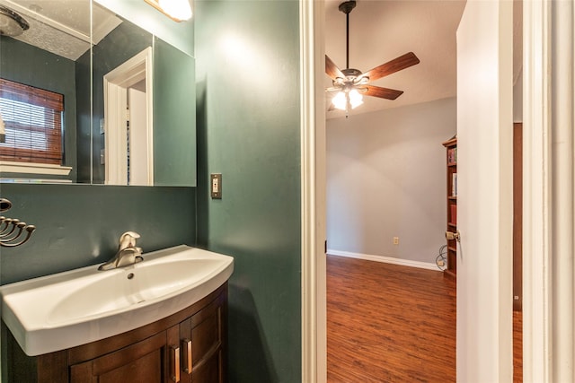 bathroom featuring baseboards, ceiling fan, wood finished floors, and vanity