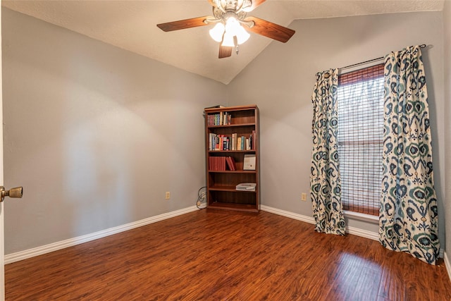 empty room featuring ceiling fan, baseboards, vaulted ceiling, and wood finished floors