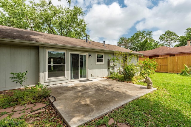 rear view of property with a patio, a lawn, and fence
