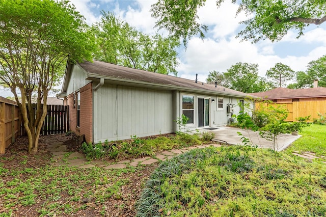 back of property featuring brick siding, a patio, and a fenced backyard