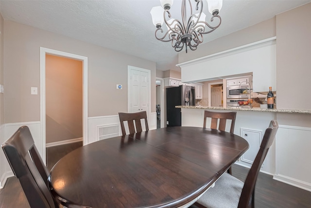 dining area with wainscoting, dark wood-style floors, and a notable chandelier