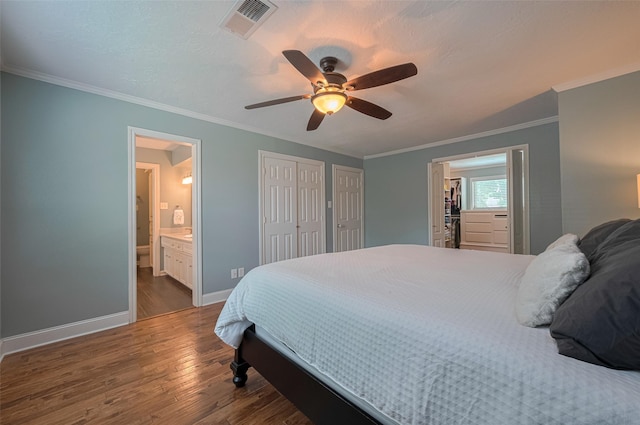 bedroom with ensuite bath, baseboards, wood finished floors, visible vents, and ornamental molding
