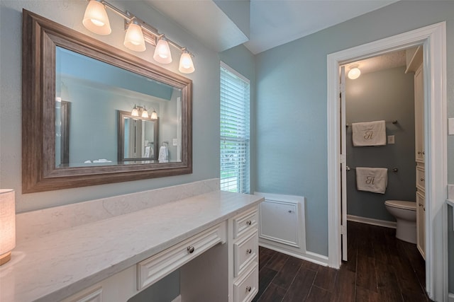 bathroom with toilet, baseboards, wood finished floors, and vanity