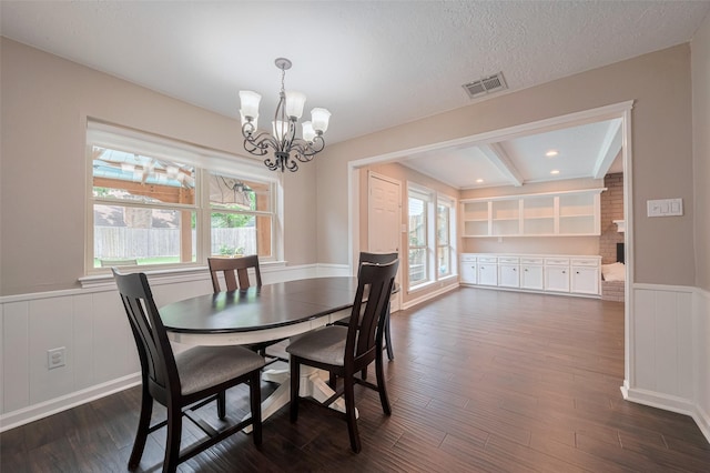 dining area featuring visible vents, wainscoting, a decorative wall, dark wood-style floors, and a notable chandelier
