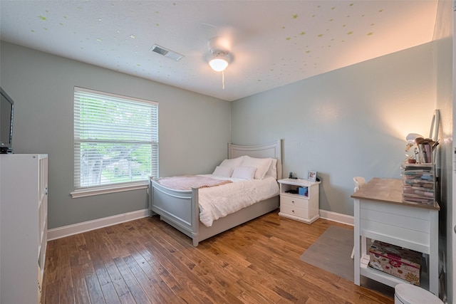 bedroom featuring a ceiling fan, baseboards, visible vents, and wood finished floors
