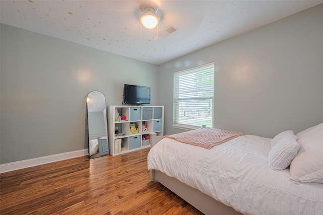 bedroom featuring a ceiling fan, baseboards, visible vents, and wood finished floors