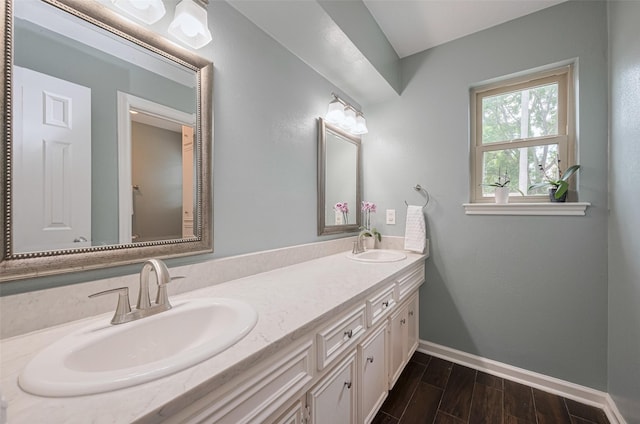 bathroom with baseboards, a sink, wood finished floors, and double vanity