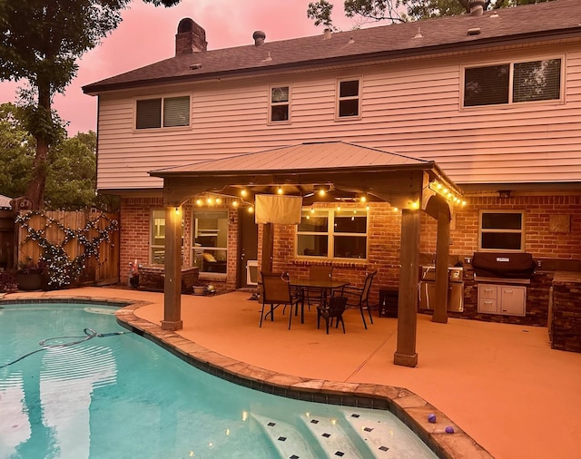 back of house at dusk featuring brick siding, fence, a fenced in pool, and a patio