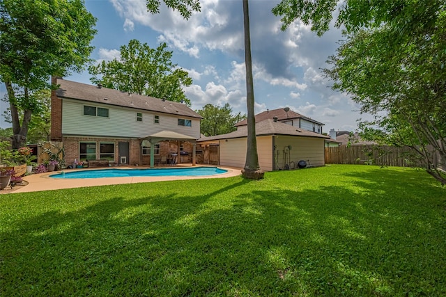 rear view of property with a fenced backyard, a lawn, brick siding, and an outdoor pool