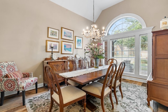 dining room with light wood-style flooring, a chandelier, and lofted ceiling