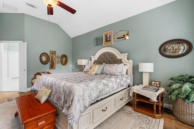 bedroom with a ceiling fan, visible vents, wood finished floors, and vaulted ceiling