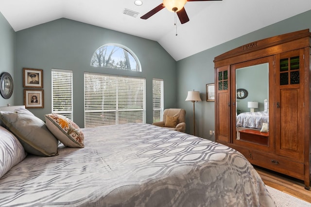 bedroom with a ceiling fan, visible vents, wood finished floors, and lofted ceiling