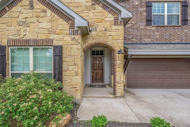 entrance to property with a garage, driveway, and stone siding