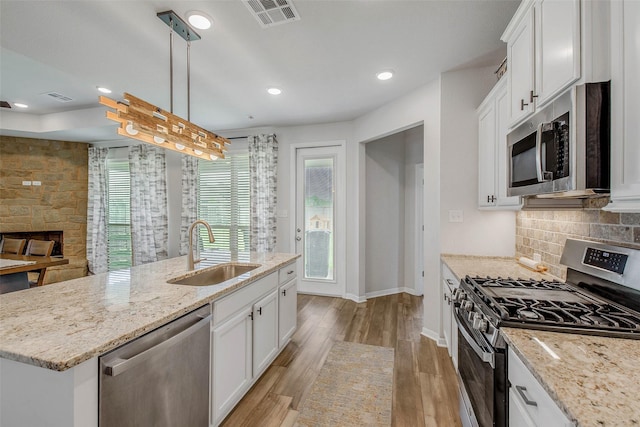 kitchen with a sink, white cabinets, stainless steel appliances, and visible vents