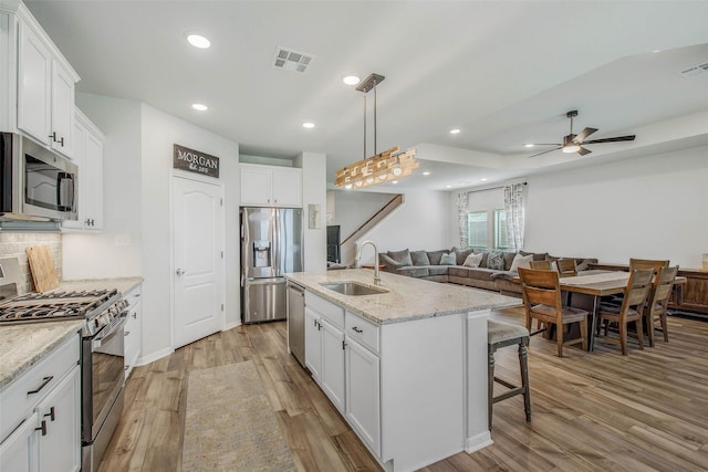 kitchen with a ceiling fan, visible vents, appliances with stainless steel finishes, a sink, and light wood finished floors