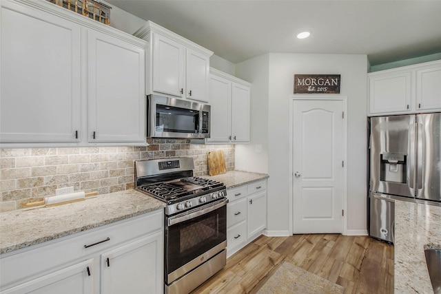kitchen featuring light wood-style floors, decorative backsplash, white cabinetry, and appliances with stainless steel finishes