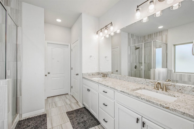full bath featuring double vanity, a sink, and a shower stall