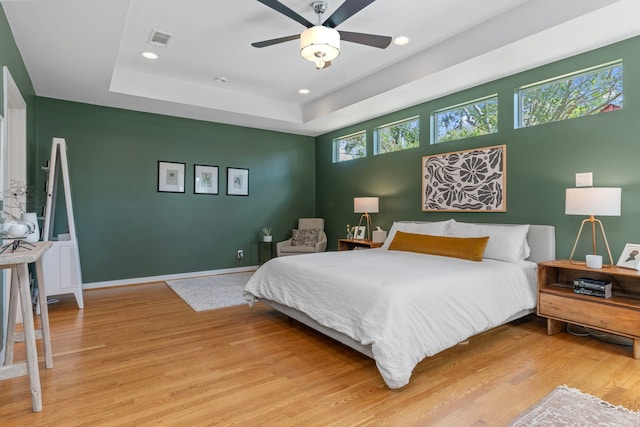 bedroom featuring a ceiling fan, visible vents, light wood-type flooring, a tray ceiling, and recessed lighting