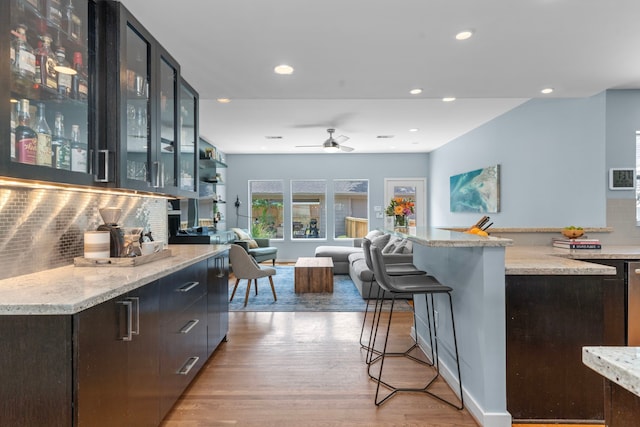 bar featuring ceiling fan, tasteful backsplash, recessed lighting, and light wood-style flooring