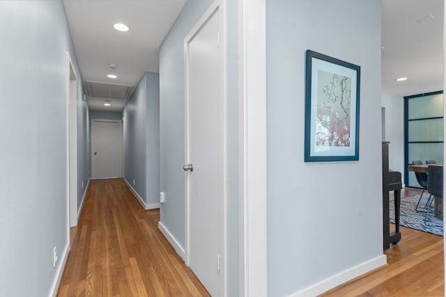 hallway with baseboards, visible vents, attic access, and light wood-style floors