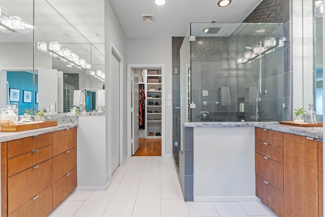 bathroom with visible vents, tile patterned flooring, vanity, a spacious closet, and a stall shower