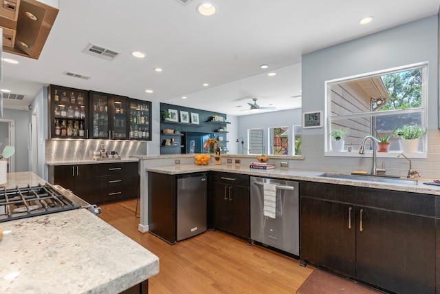 kitchen featuring stainless steel dishwasher, visible vents, a sink, and light wood-type flooring