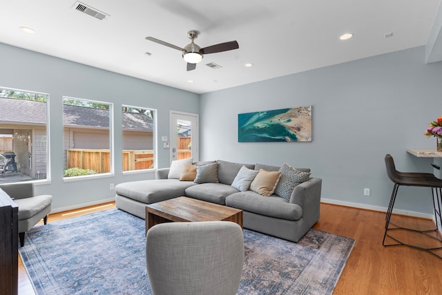 living area with baseboards, a ceiling fan, wood finished floors, and visible vents