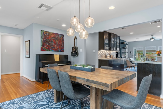 dining area with baseboards, ceiling fan, light wood-type flooring, and visible vents