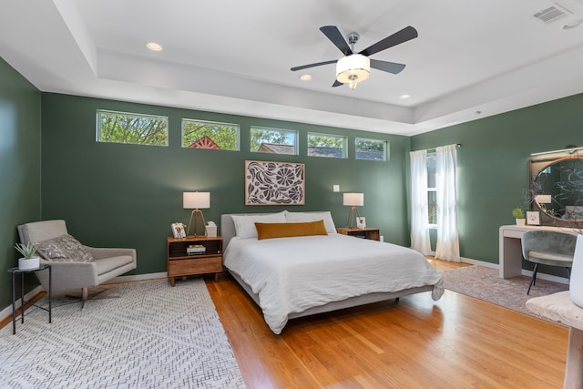 bedroom with baseboards, multiple windows, a tray ceiling, and visible vents