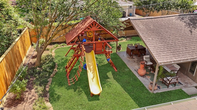 view of playground featuring a fenced backyard, a yard, and a patio area