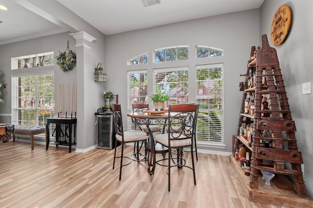 9614 Oconnor Ln, Missouri City, TX 77459 - dining area featuring light wood-style flooring, baseboards, wine cooler, visible vents, and ornamental molding