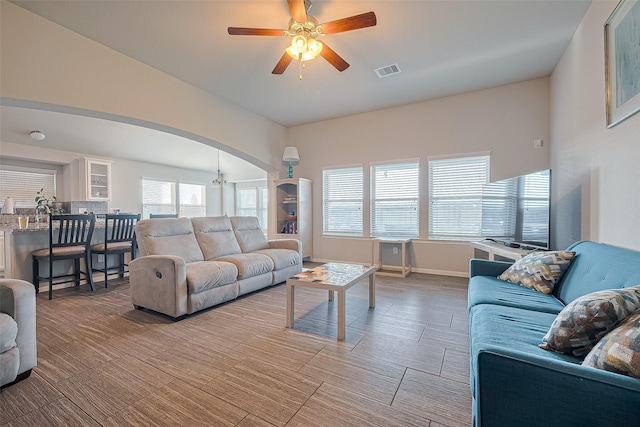 living area with visible vents, arched walkways, baseboards, and ceiling fan