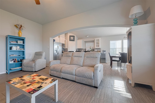 living room with arched walkways, ceiling fan, and baseboards