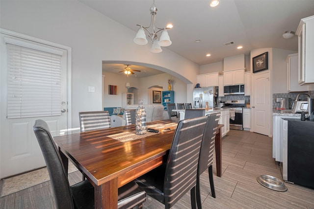 dining space featuring visible vents, arched walkways, ceiling fan with notable chandelier, and lofted ceiling