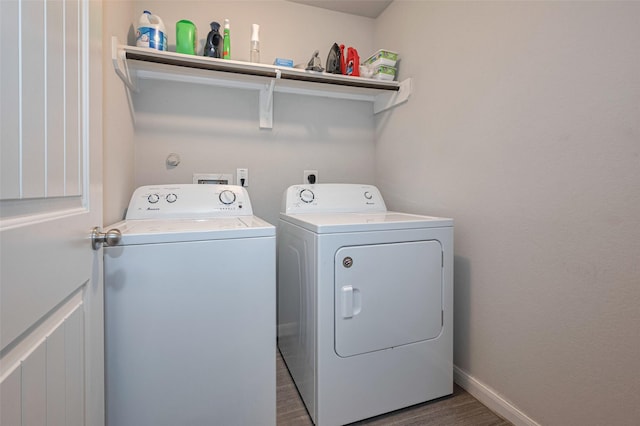 washroom featuring laundry area, washer and clothes dryer, baseboards, and dark wood-type flooring