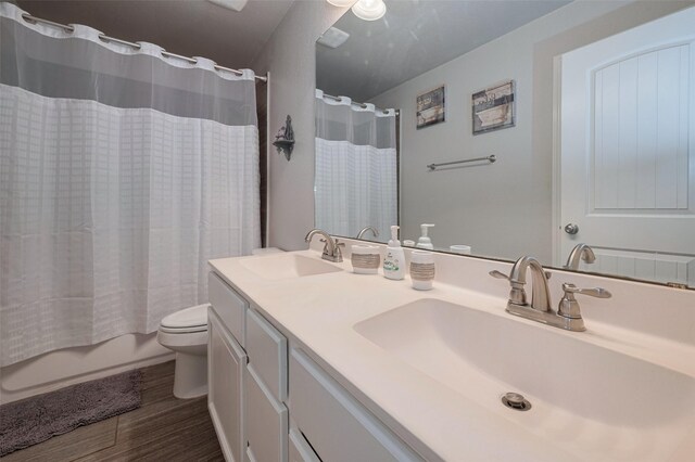 full bathroom featuring double vanity, a sink, wood finished floors, and toilet