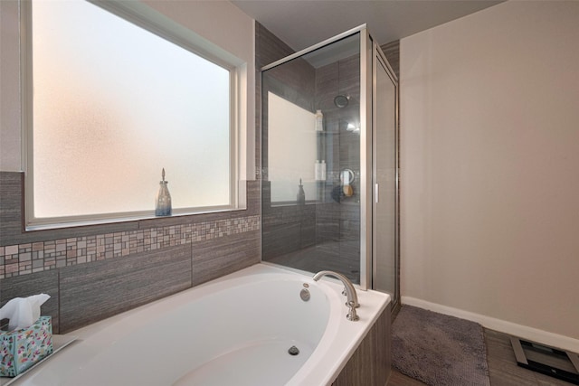 full bath with baseboards, a stall shower, and a garden tub