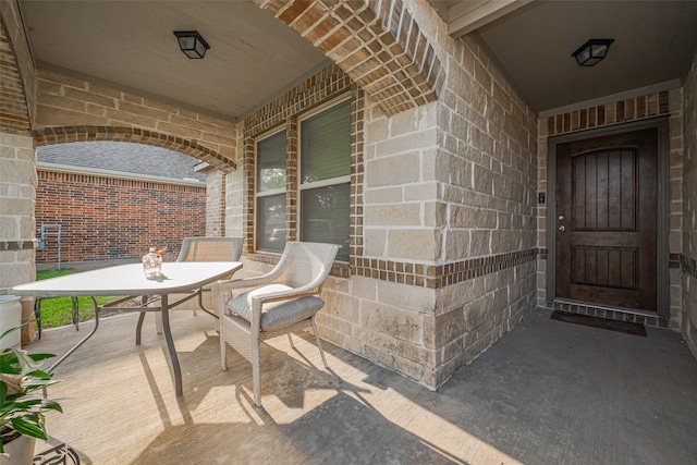 view of exterior entry with outdoor dining space and brick siding