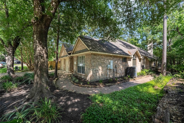 54 N Crossed Birch Pl, The Woodlands, TX 77381 - view of home's exterior with central AC unit, a chimney, and brick siding
