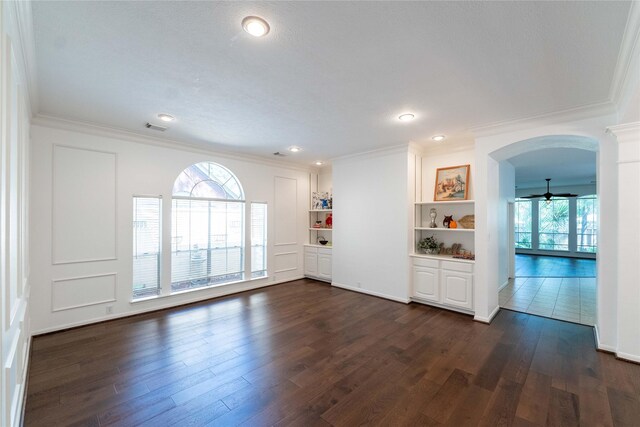 54 N Crossed Birch Pl, The Woodlands, TX 77381 - unfurnished living room featuring crown molding, arched walkways, dark wood finished floors, and visible vents