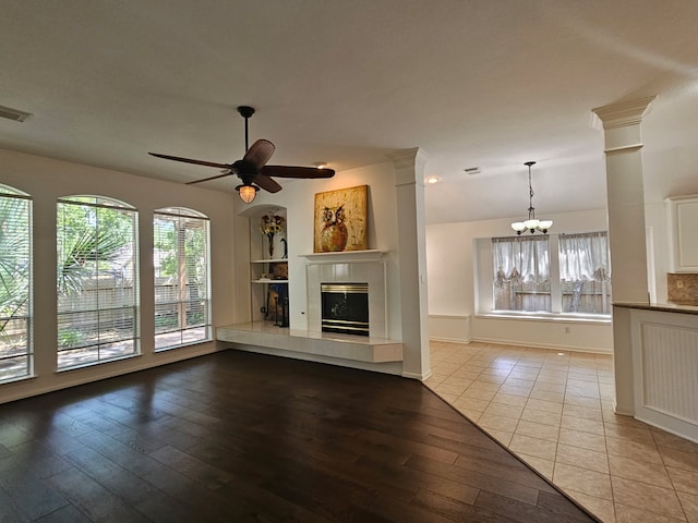 54 N Crossed Birch Pl, The Woodlands, TX 77381 - unfurnished living room featuring plenty of natural light, a glass covered fireplace, ceiling fan with notable chandelier, and hardwood / wood-style floors