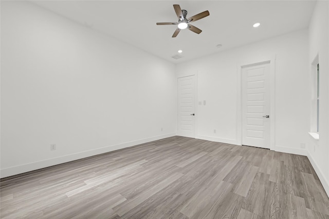 spare room with wood finished floors, a ceiling fan, recessed lighting, and baseboards