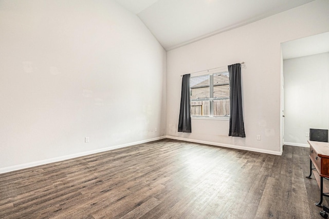 empty room with baseboards, vaulted ceiling, and dark wood-type flooring