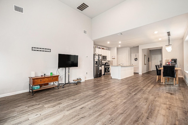 living area featuring visible vents, recessed lighting, baseboards, and wood finished floors