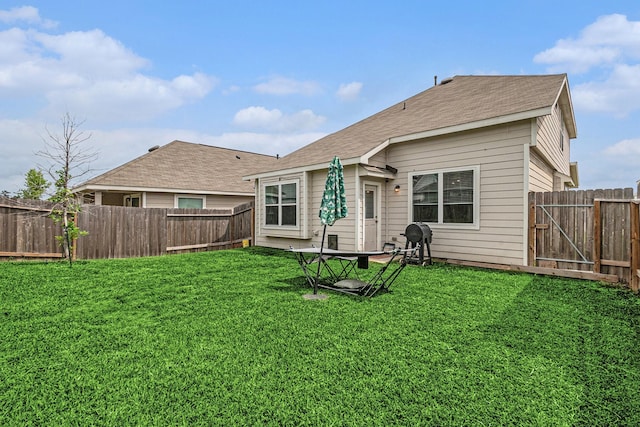 back of house featuring a fenced backyard, a yard, and roof with shingles