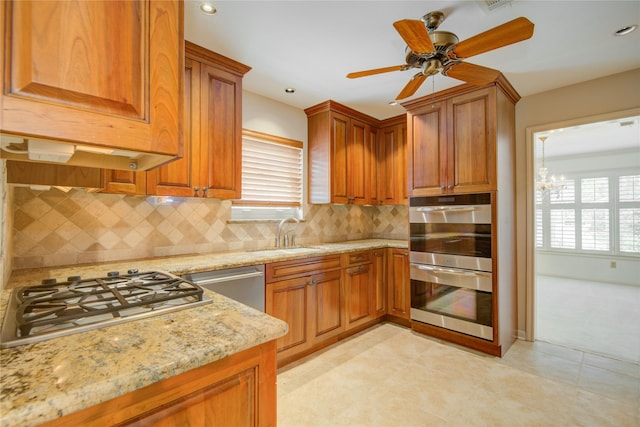kitchen with stainless steel appliances, light stone countertops, a healthy amount of sunlight, and a sink