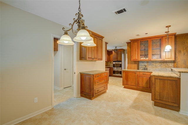 kitchen featuring light stone countertops, double oven, brown cabinets, and visible vents