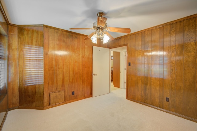 spare room featuring wooden walls, carpet floors, and ceiling fan